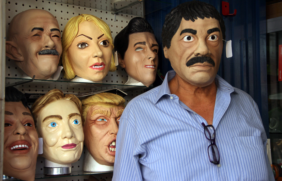 Shopkeeper Manuel Robles (R) poses with a latex mask depicting Mexican drug trafficker Joaquin Guzman Loera -aka 