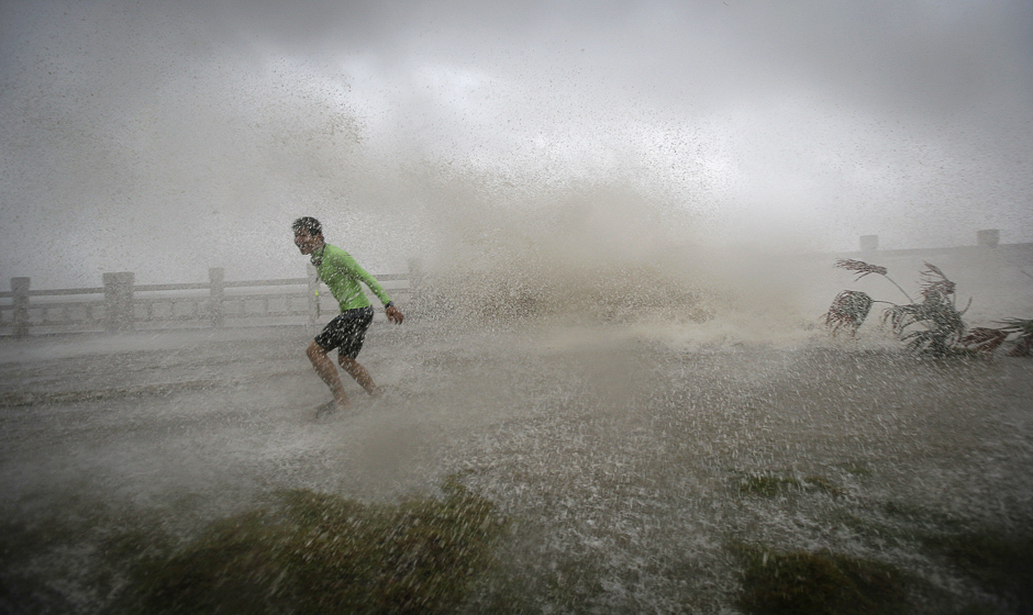 A man playing with waves runs way from a wave at a beach as Typhoon Sarika lands in Wanning, Hainan province, China. PHOTO: REUTERS