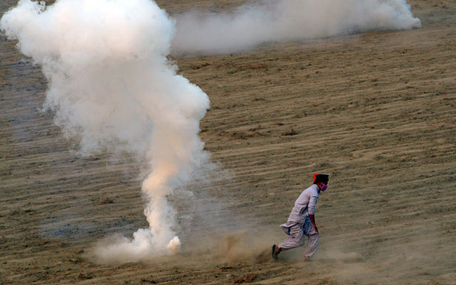 an activist of tehreek e insaf pti runs from tear gas shells during clashes with police in swabi on october 31 2016 photo afp