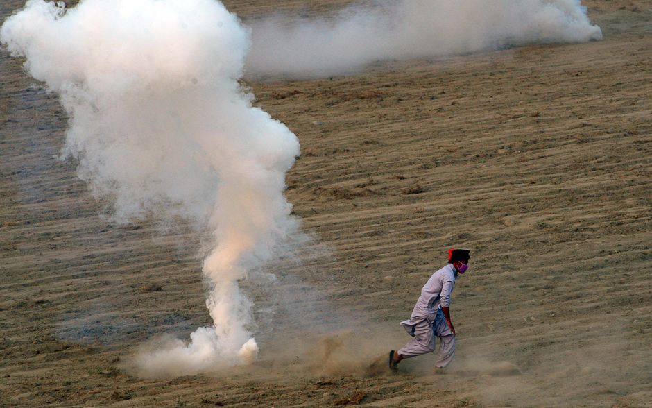 An activist of opposition party Tehreek-i-Insaf (PTI) runs from tear gas shells during clashes with police in Swabi on October 31, 2016. Police in Pakistan fired teargas on thousands of opposition supporters who tried to remove barricades while marching towards capital Islamabad, an AFP reporter said. PHOTO: AFP