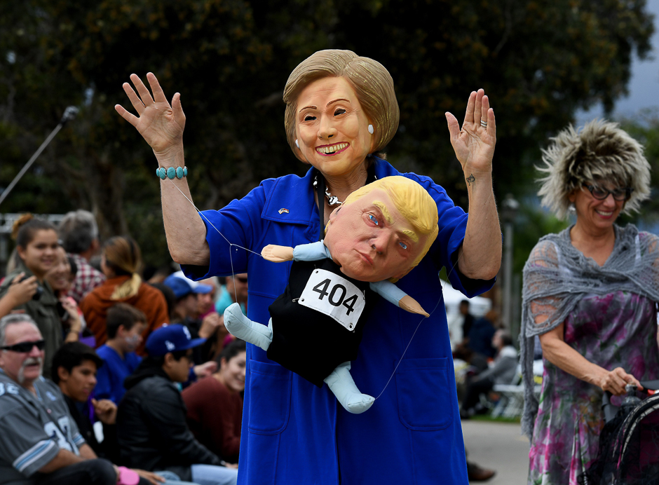 A woman wearing a Hillary Clinton mask carries a Republican presidential nominee Donald Trump doll during a Halloween parade in Long Beach, California. PHOTO: AFP