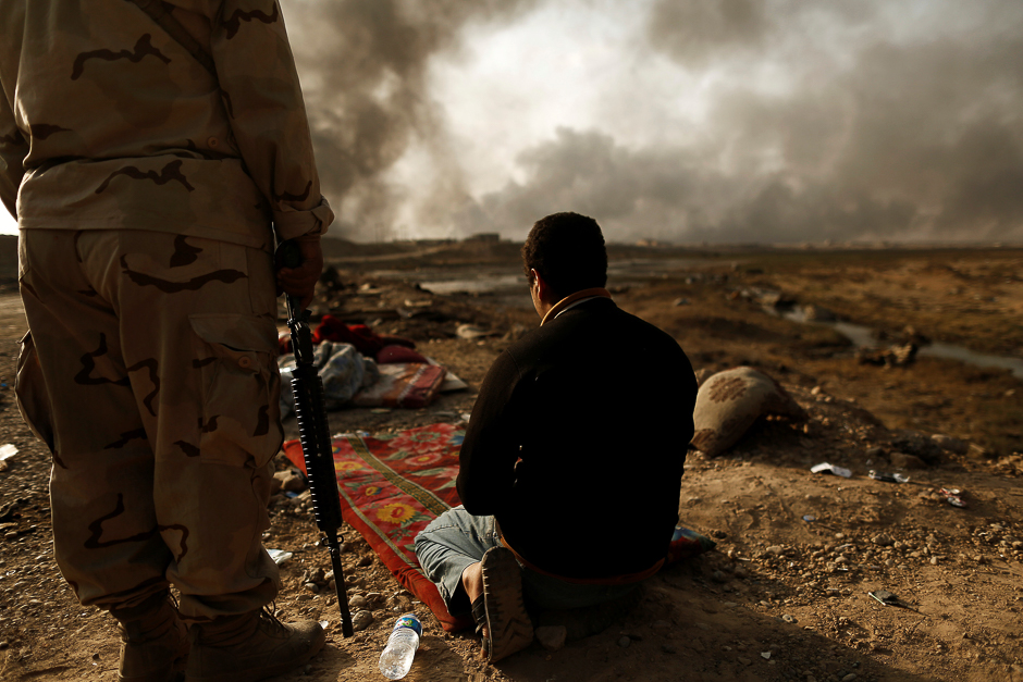An Iraqi soldier stands next to a detained man accused of being an Islamic state fighter. PHOTO: REUTERS