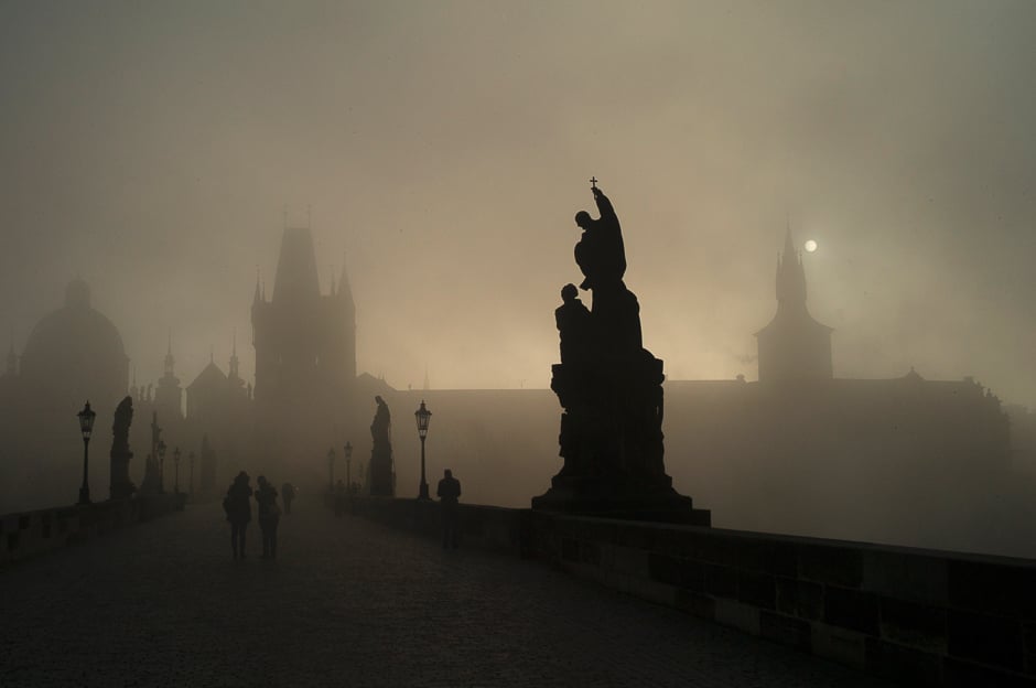 Tourists walk across on the Charles Bridge on a foggy morning in Prague. PHOTO: AFP