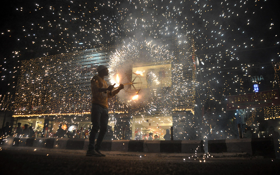 An Indian worker bursts firecrackers during a fireworks display at a local marketplace on the eve of Diwali festival in Jammu. Diwali, the Hindu festival of lights, will be celebrated. PHOTO: AFP