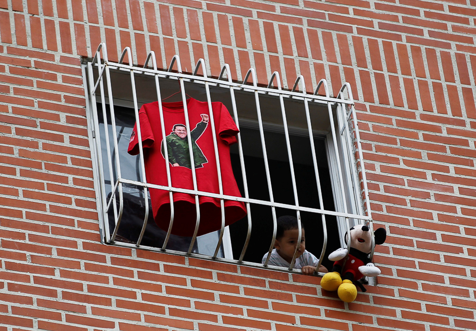 A child is seen at a window next to a t-shirt with an image depicting the late president Hugo Chavez. PHOTO: REUTERS