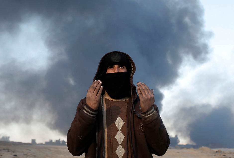 An oil worker gestures in front of oilfields burned by Islamic State fighters in Qayyara, south of Mosul, Iraq. PHOTO: REUTERS