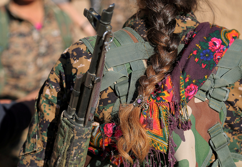 A Syrian Democratic Forces (SDF) female fighter's braid is pictured while she is carrying her weapon in Tal Samin village, north of Raqqa city, Syria. PHOTO: REUTERS