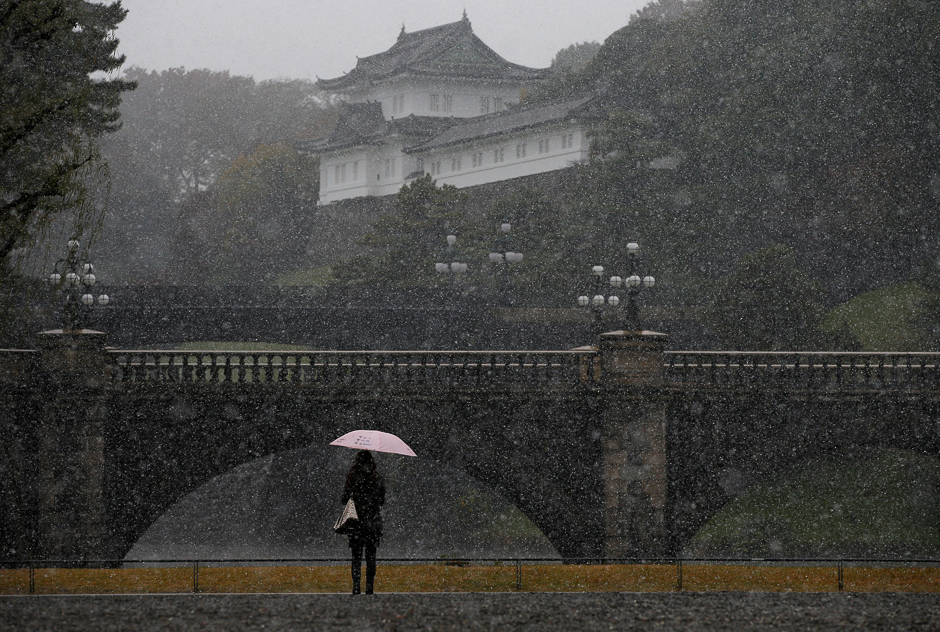 A tourist is seen during the first November snowfall in 54 years in Tokyo, at the Imperial Palace in Tokyo, Japan. PHOTO: REUTERS