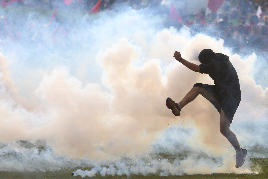 An anti-government demonstrator kicks back a tear gas canister during a clash with riot policemen during a protest against a constitutional amendment, known as PEC 55, that limits public spending, in front of Brazil's National Congress in Brasilia, Brazil. PHOTO: REUTERS