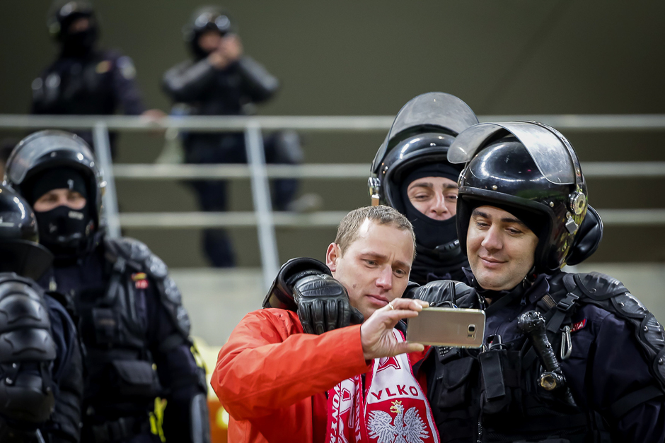 A Polish fan takes a selfie with Romanian riot police officers during the 2018 FIFA World Cup qualification football match between Romania and Poland. PHOTO: AFP