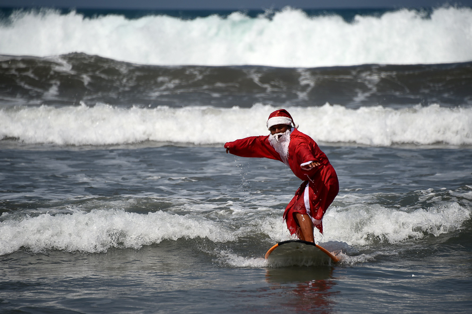 A surfer dressed in a Santa Claus outfit surfs on Kuta beach on Indonesia's resort island of Bali. PHOTO: AFP