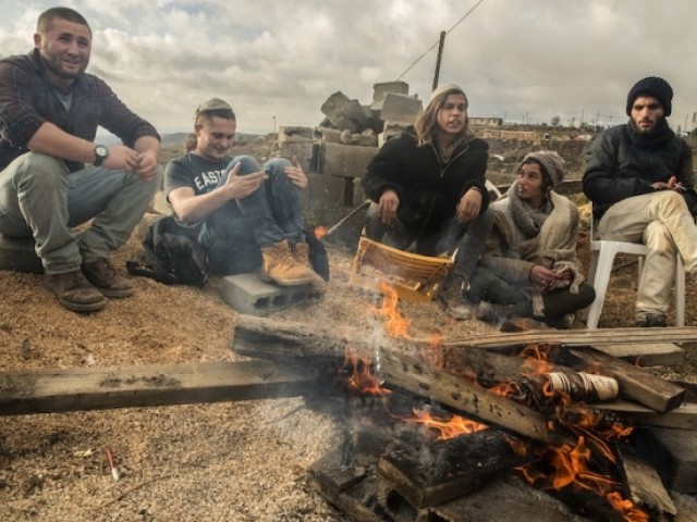 Young Israeli settlers accumulate around a glow in a allotment outpost of Amona, that was determined in 1997 and built on private Palestinian land, in a Israeli-occupied West Bank on Dec 18, 2016. PHOTO: AFP