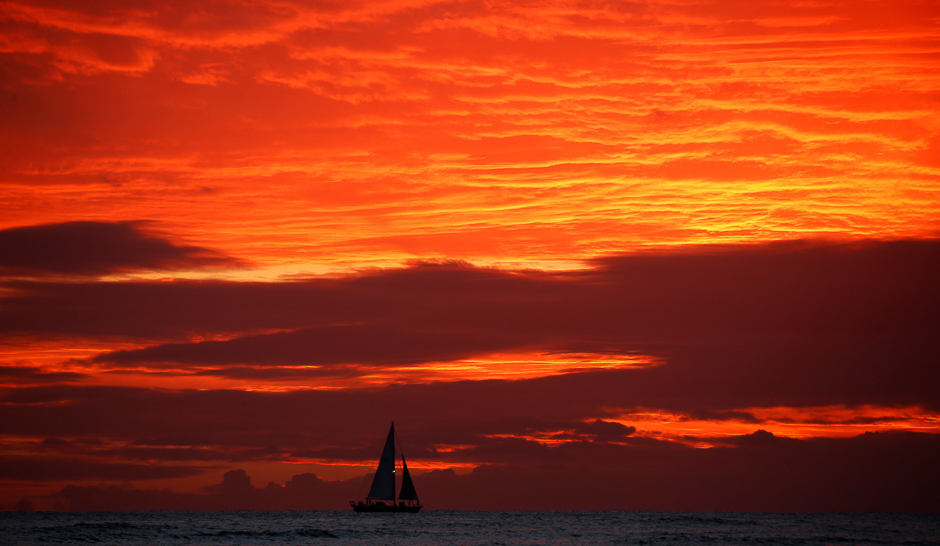 A sailboat passes in front of clouds lit up by the sunset sky off Waikiki in Hawaii, US. PHOTO: REUTERS
