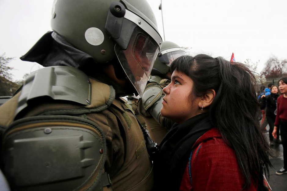 A demonstrator looks at a riot policeman during a protest marking the country's 1973 military coup in Santiago, Chile September 11, 2016. PHOTO: REUTERS