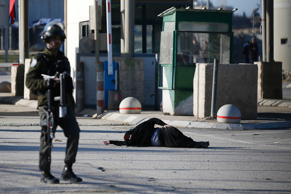 A Palestinian woman lies on the ground after she was shot and wounded by Israeli security forces while approaching the Qalandia checkpoint with a knife, between Jerusalem and the occupied West Bank. PHOTO: AFP