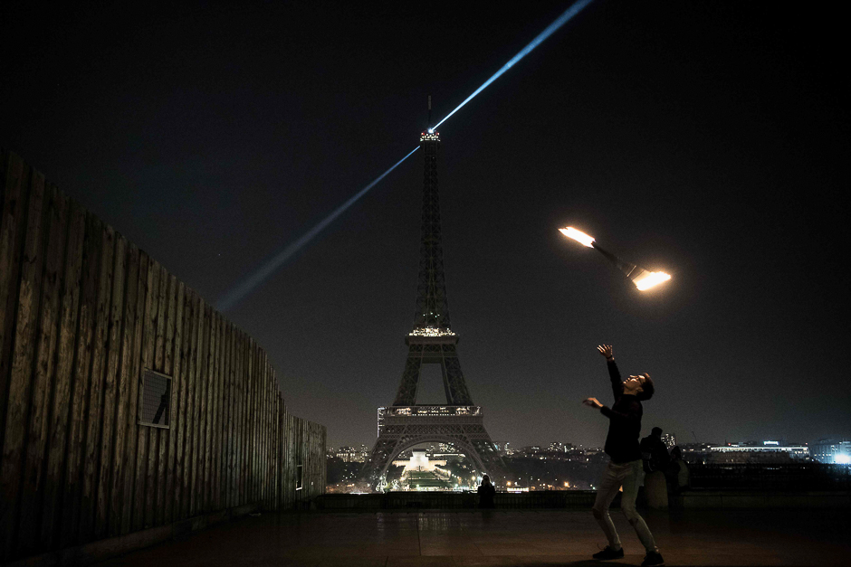 A man juggles with a stick on fire in front of the Eiffel tower with lights off, in Paris in support of the Syrian city of Aleppo. PHOTO: AFP