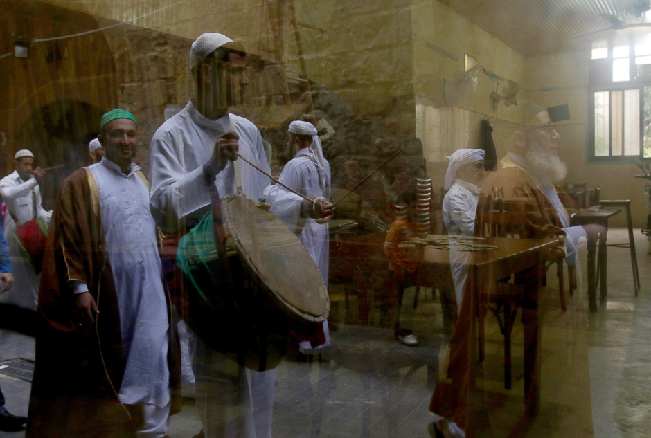 A reflection in a glass window shows Lebanese Muslim Sufi men playing music during a ritual ceremony. PHOTO: AFP