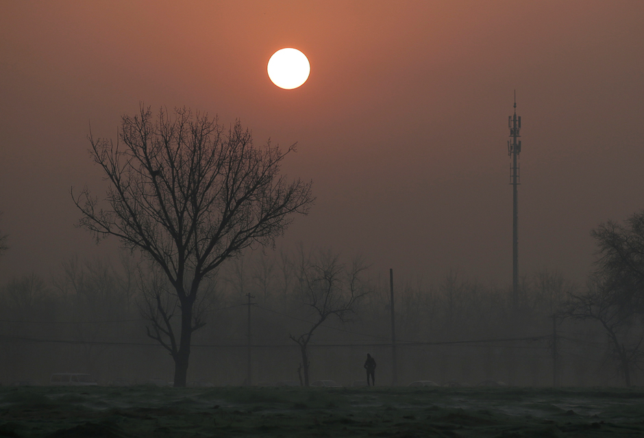 A man walks during sunrise in smog on a polluted day as a red alert issued for air pollution in Beijing, China. PHOTO: REUTERS