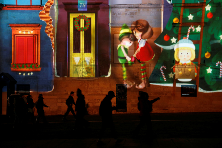 People walk past 3D projections designed by students of the Malta College of Arts, Science and Technology are projected onto the facade of the Presidential Palace as part of Christmas and New Year celebrations in Valletta, Malta. PHOTO: REUTERS