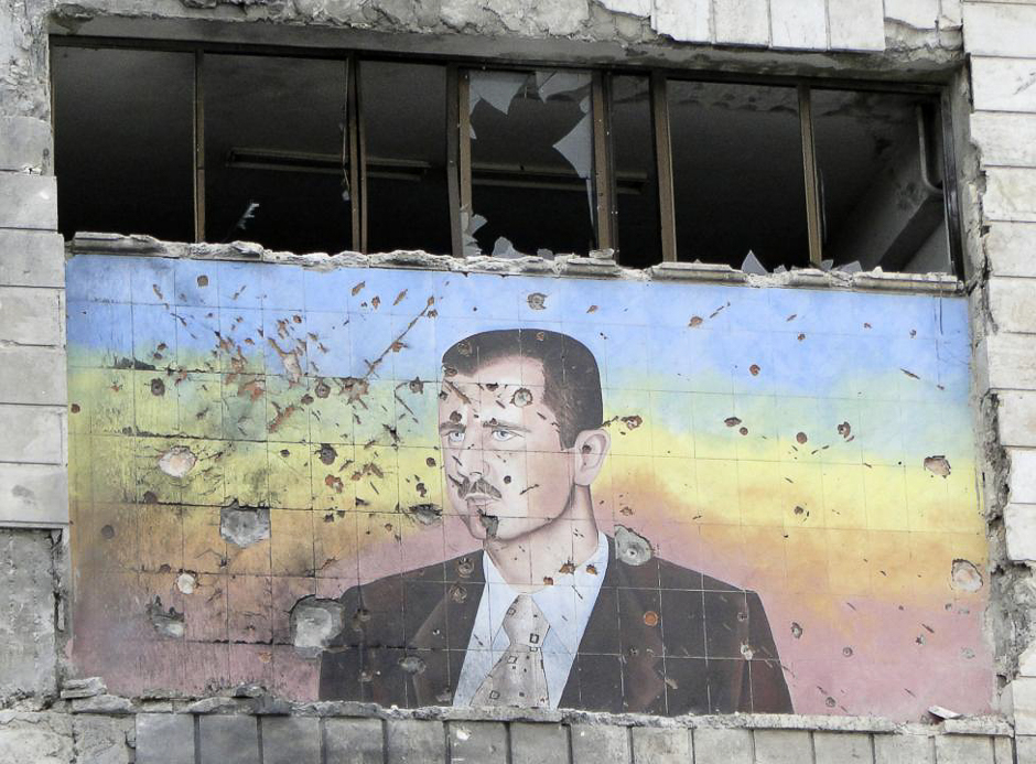 A picture of Syria's President Bashar al-Assad riddled with holes is seen on the facade of the police academy in Aleppo, after it was captured by Free Syrian Army fighters, March 4, 2013. PHOTO: REUTERS