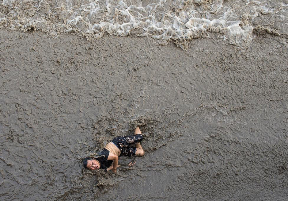 A man who fell off a bridge while waiting to watch tidal wave struggles as waves come towards him, on the banks of Qiantang River in Hangzhou, Zhejiang province, China, July 25, 2016. PHOTO: REUTERS 