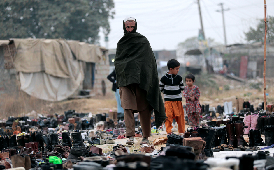 A customer looks at shoes for the winter with his children at a used shoe market in Islamabad, Pakistan November 22, 2016. REUTERS/Caren Firouz
