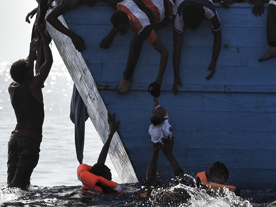 Migrants try to pull a child out of the water as they wait to be rescued by members of Proactiva Open Arms NGO in the Mediterranean sea, some 12 nautical miles north of Libya, on October 4, 2016. PHOTO: AFP