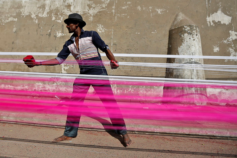 A worker applies colour to strings, which will be used to fly kites, on a roadside in Ahmedabad, India. PHOTO: REUTERS