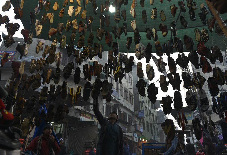 A Pakistani shopkeeper adjusts shoes at his shoe stall in Lahore. PHOTO: AFP