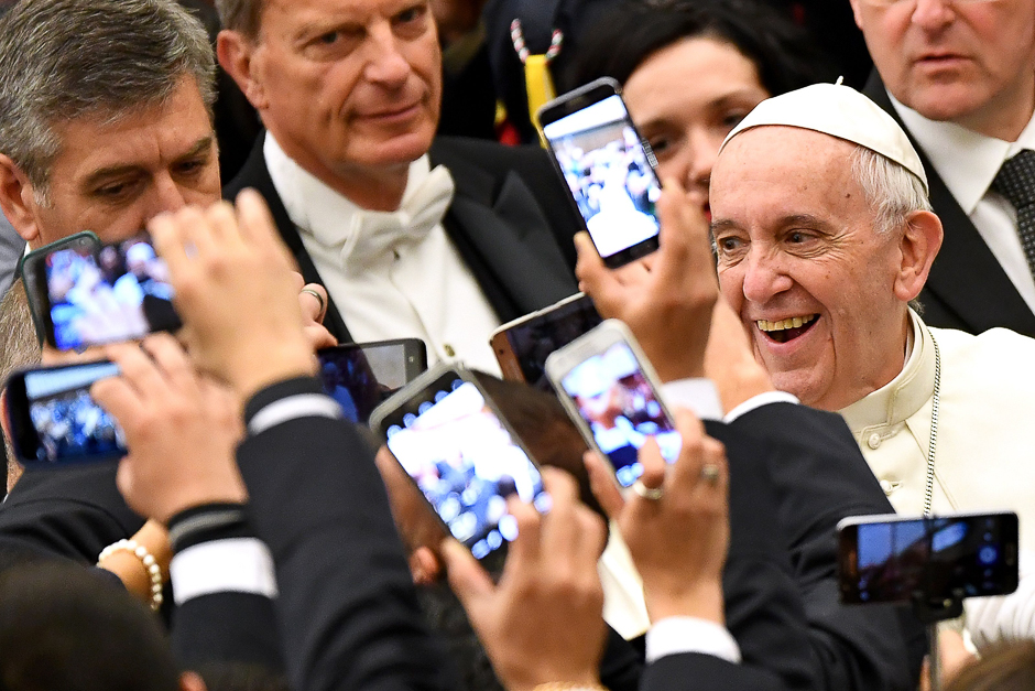 Pope Francis (R) arrives to lead his weekly general audience at Paul VI hall at the Vatican as people take pictures of him with their cell-phone. PHOTO: AFP