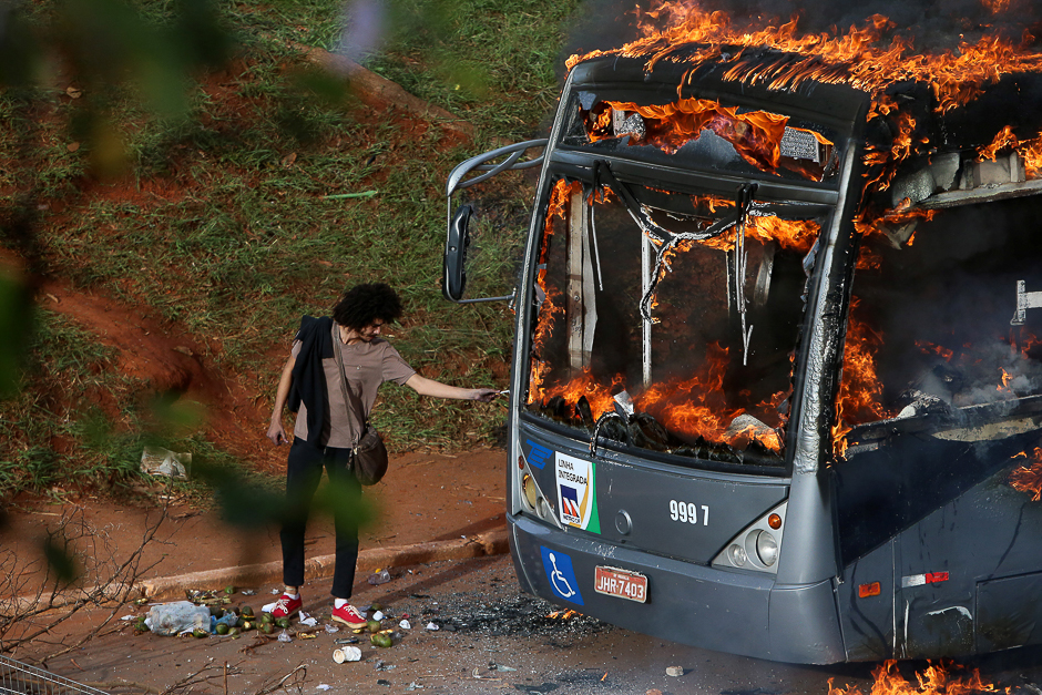 A man lights up his cigarette with the flames of a bus burned by anti-government demonstrators during a protest against the constitutional amendment PEC 55, which limits public spending, in front of Brazil's National Congress in Brasilia, Brazil. PHOTO: REUTERS