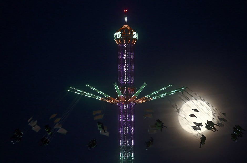 People on a funfair ride are silhouetted against the moon a day before the âsupermoonâ spectacle, in London, Britain. PHOTO: REUTERS