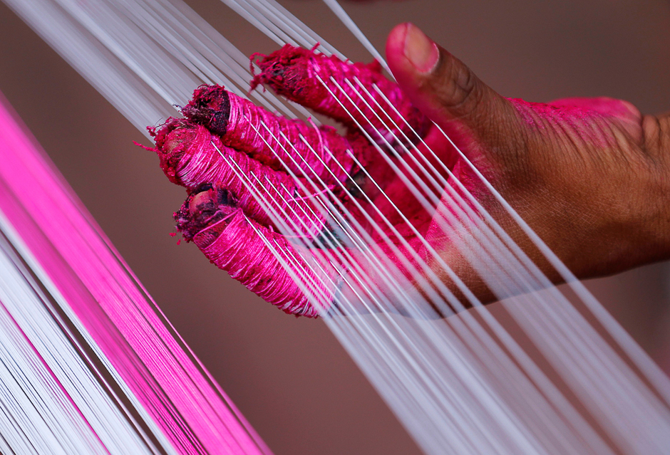 A worker applies colour to strings, which will be used to make kites, alongside a road in Ahmedabad, India. PHOTO: REUTERS