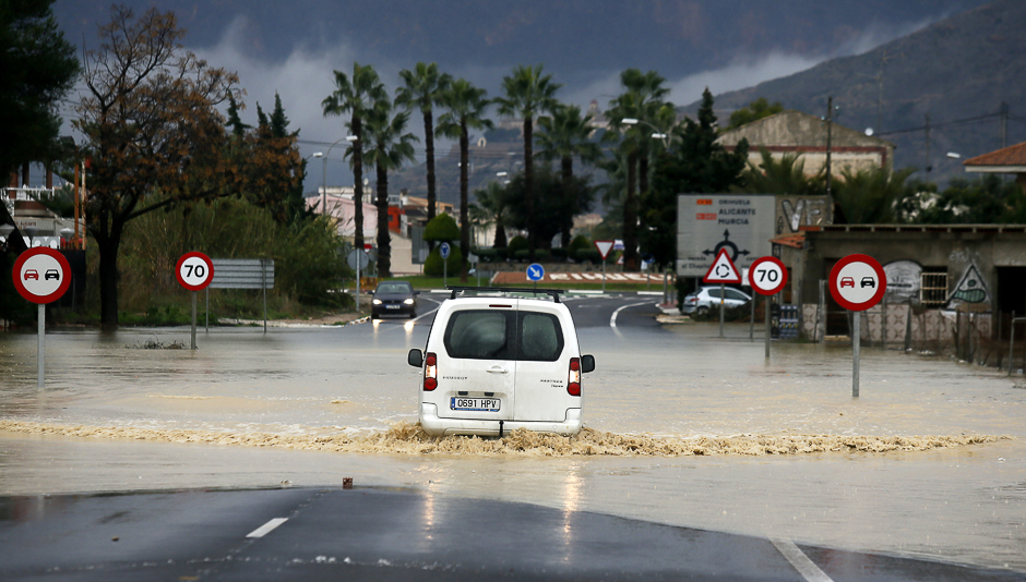 A car reverses through floodwaters following heavy rains in Orihuela on December. PHOTO: AFP