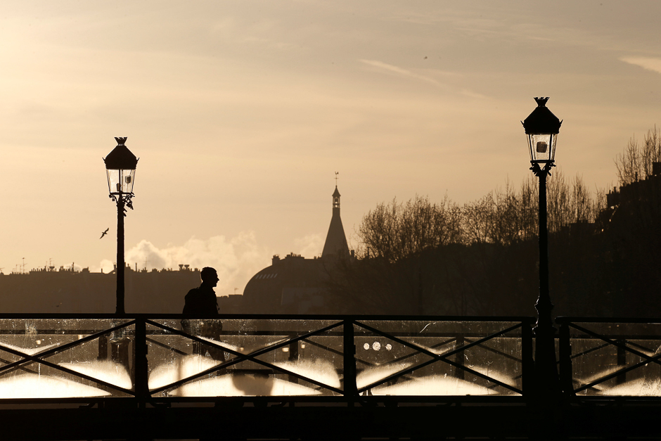 A man walks on the Pont des Arts bridge as the sun rises above the Seine River skyline in central Paris, France. PHOTO: REUTERS