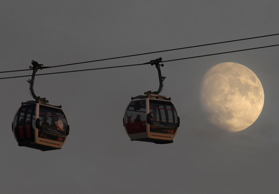 Passengers cross the River Thames in cable cars with the moon seen behind at Greenwich Peninsula in London, Britain. PHOTO: REUTERS
