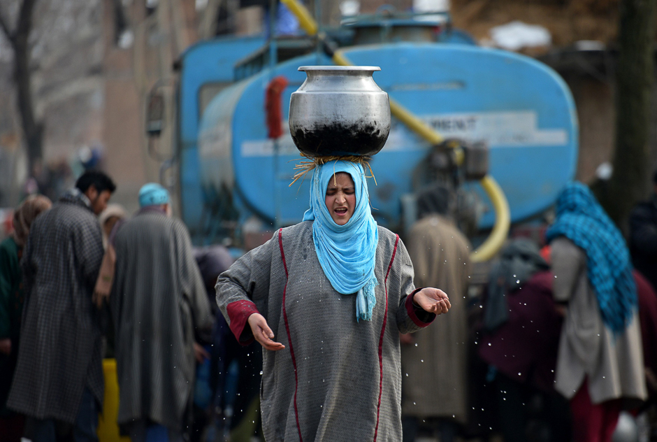 A Kashmiri woman carries a water utensil filled from a water tanker on the outskirts of Srinagar. PHOTO: AFP