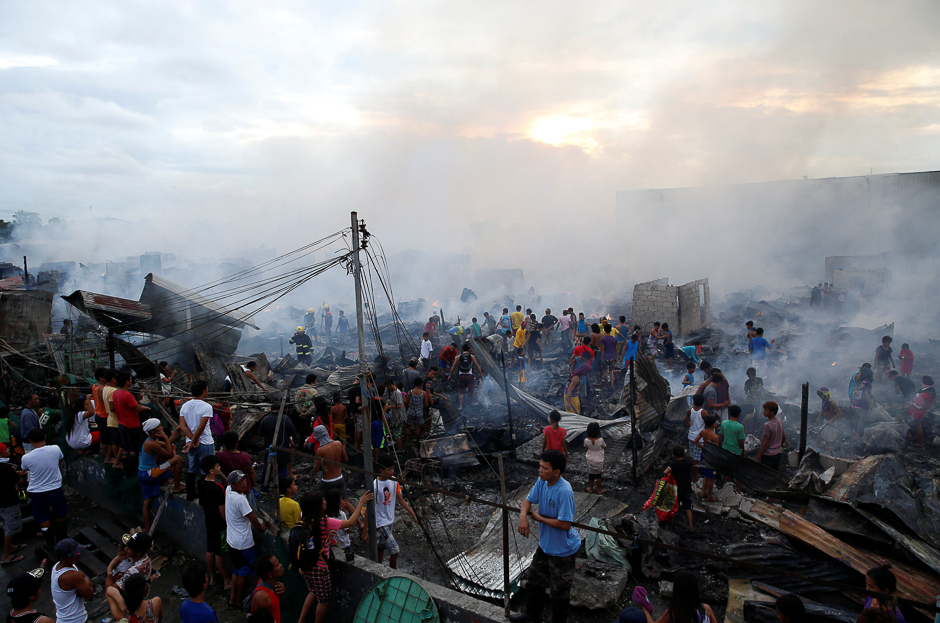 Residents gather at the ruins of their homes after a fire at a squatter colony in Navotas, Metro Manila in the Philippines. PHOTO: REUTERS