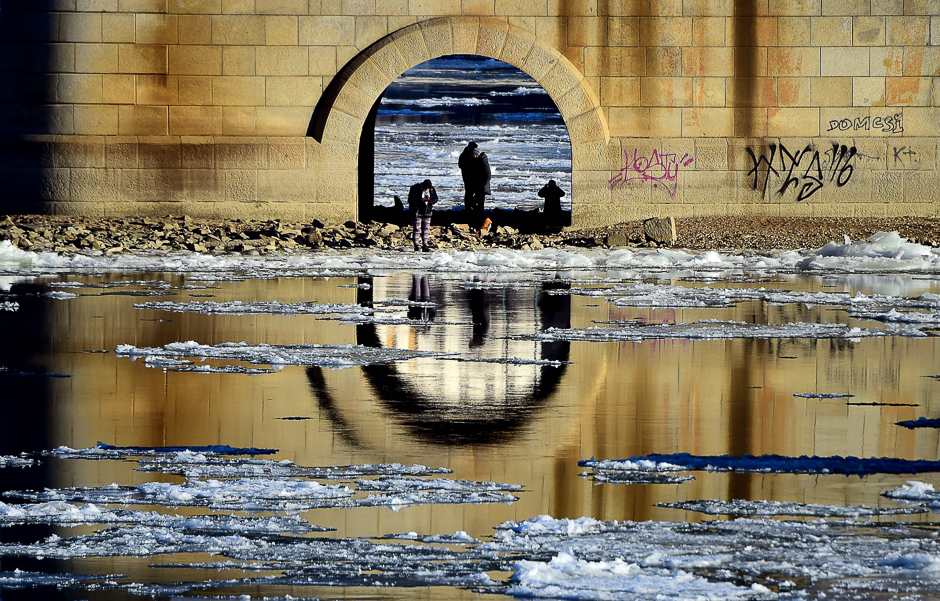 Locals walk under the stone-pillar of the Margaret Bridge at Budapest downtown as ice floes float in the water of the River Danube, when the extreme winter temperature overtakes a new record in the capital with minus 18,6 degrees centigrade. PHOTO: AFP