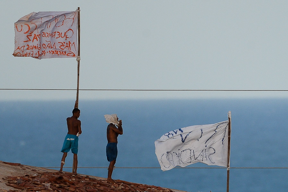 Prisoners atop the roof of the compound celebrate the transfer of their leaders after a negotiation with the police at the Alcacuz Penitentiary, near Natal, Rio Grande do Norte. PHOTO: AFP