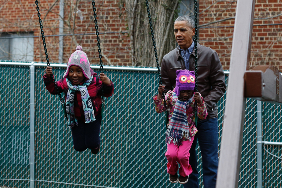 US President Barack Obama plays with children on a swing donated by the first family at the Jobs Have Priority Shelter in Washington, DC. PHOTO: AFP