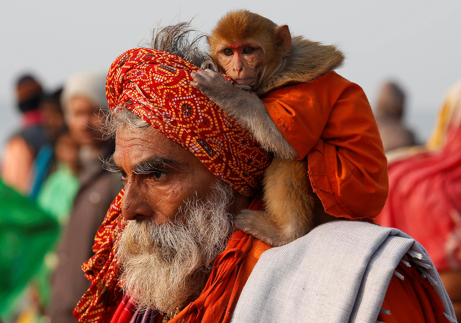 A Sadhu or a Hindu holy man carrying his pet monkey walks after taking a dip at the confluence of the river Ganges and the Bay of Bengal on the occasion of 