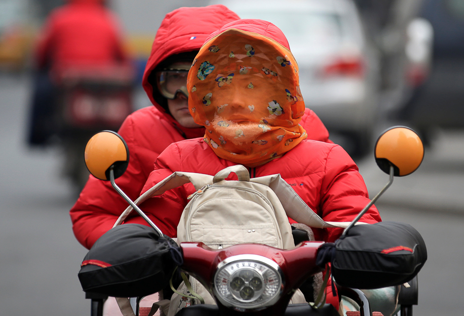 A woman covered with a scarf drives along a road on a winter day in Beijing, China. PHOTO: REUTERS