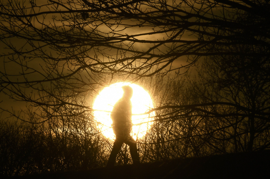 A walker is silhouetted in front of the setting sun on Primrose Hill in London, Britain. PHOTO: REUTERS