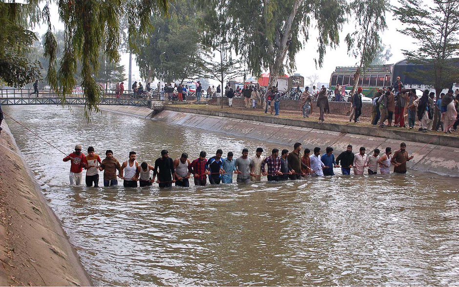 Rescue workers and locals search for the dead body of a young boy who drowned in Rakh Branch Canal after a car accident, Faisalabad. PHOTO: APP