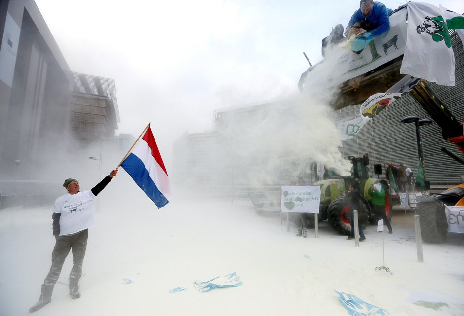 A milk producer waves a Dutch flag as farmers spray powdered milk to protest against dairy market overcapacity outside a meeting of European Union agriculture ministers in Brussels, Belgium. PHOTO: REUTERS