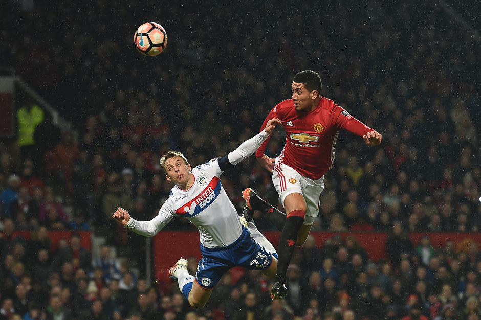 Manchester United's English defender Chris Smalling (R) heads the ball in to score their second goal during the English FA Cup fourth round football match between Manchester United and Wigan Athletic at Old Trafford in Manchester, north west England. PHOTO: AFP