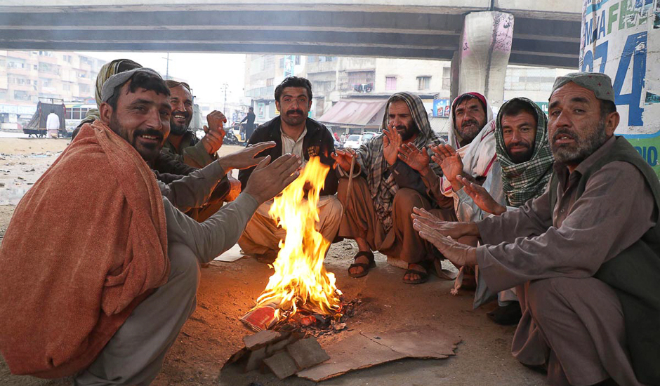 Locals set fire to warm themselves during the rain. PHOTO: ONLINE/SABIR MAZHAR