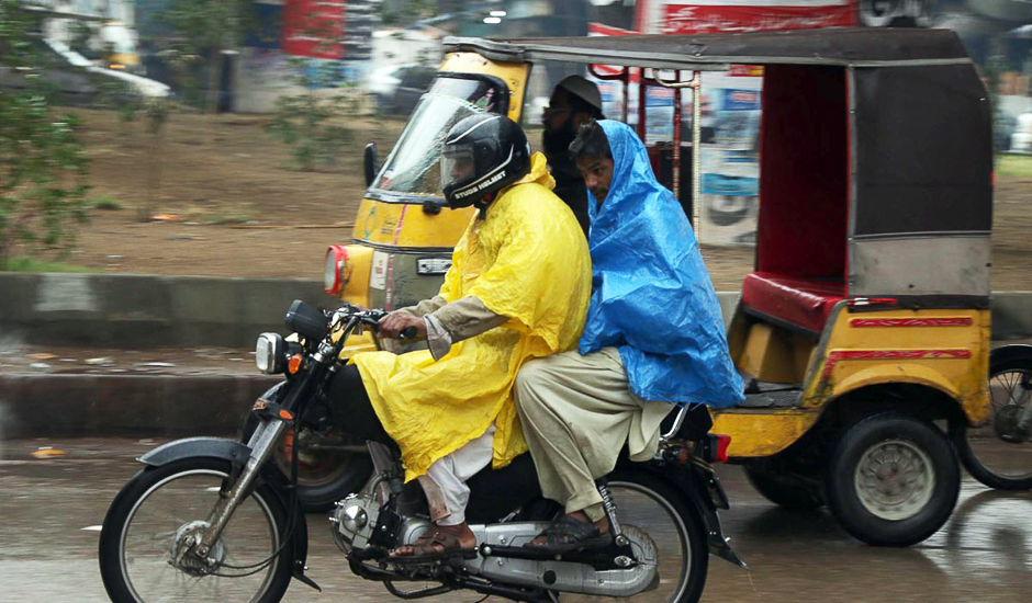 Motorist wear plastic sheets during the rain in the port city. PHOTO: ONLINE/SABIR MAZHAR