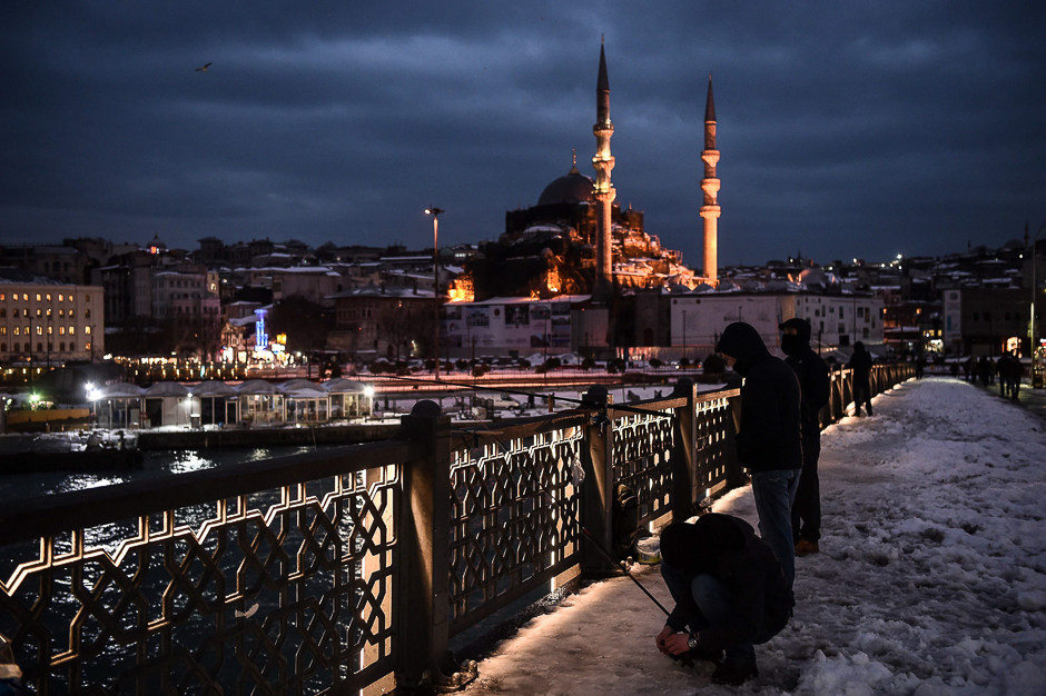 Men fish along the Galata Bridge in the Karakoy district of Istanbul following a snow storm. PHOTO: AFP